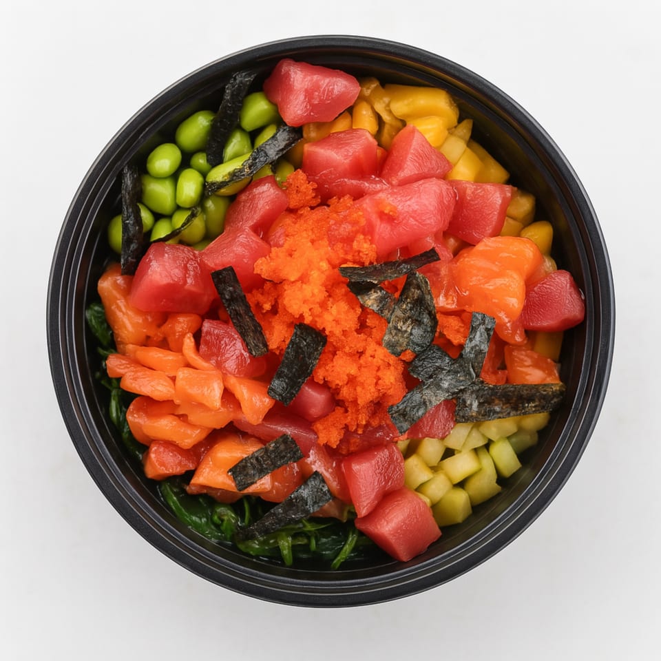 Overhead view of a colorful poke bowl with tuna, salmon, edamame, corn, and seaweed.